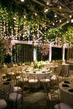 tables and chairs are set up for an outdoor event with lights strung from the ceiling