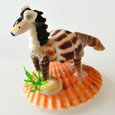 a small figurine of a sea horse on an orange shell