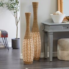 two tall vases sitting next to each other on a wooden floor near a table