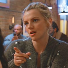 a woman is talking to someone while sitting at a table with other people in the background