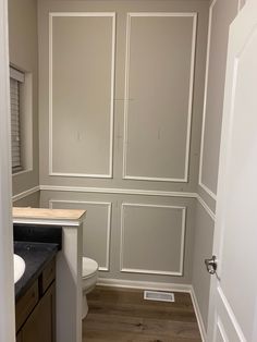 an empty bathroom with white walls and wood flooring