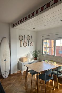 a dining room with a surfboard on the wall and wooden flooring in front of it