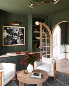 a living room with green walls and white furniture in the center, surrounded by arched doorways