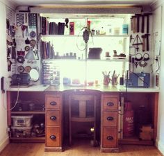 a desk with lots of clutter on top of it in front of a window