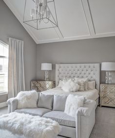 a large white couch sitting under a chandelier next to a bed in a bedroom