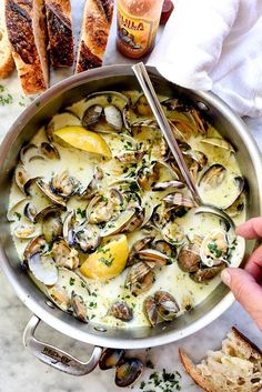 a pan filled with clams and bread on top of a marble counter next to a bottle of beer