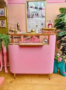 a pink ice cream stand in the corner of a room filled with potted plants