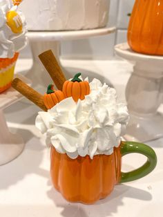 an orange mug filled with whipped cream and pumpkins on top of a white table