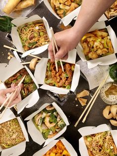 several people holding chopsticks over some food