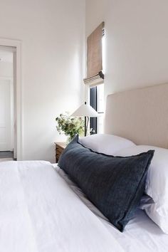 a bed with white linens and pillows in a small room next to a door