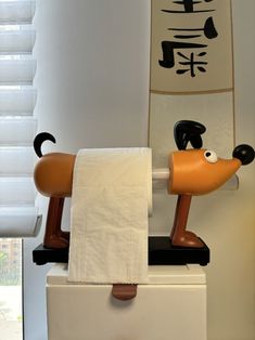 a toilet with a towel hanging on it's side and a cartoon dog sitting on top of it