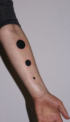 a person with a black dot tattoo on their arm