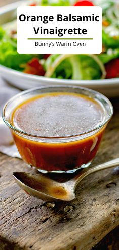 an orange balsamic vinaigrette in a bowl next to a salad