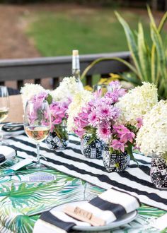 the table is set with black and white striped napkins, wine glasses, and flowers in vases