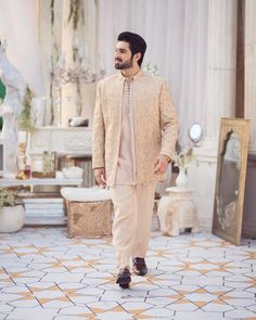 a man standing in front of a mirror wearing a beige suit and black loafs