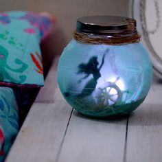 a glass jar filled with water sitting on top of a wooden table next to pillows