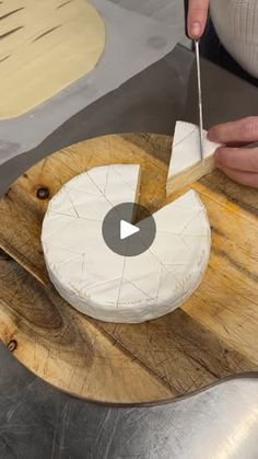 a person cutting cheese on top of a wooden board