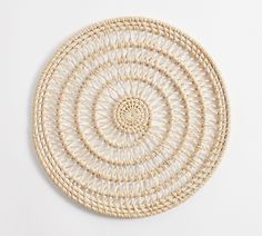 a round woven wall hanging on a white wall