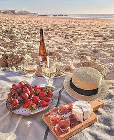 two glasses of wine, strawberries and cheese on the beach