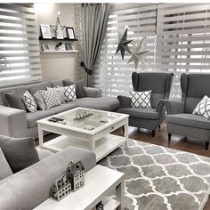 a living room filled with gray couches and white coffee table in front of a window