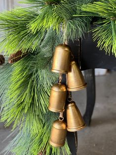 a bunch of bells that are hanging from a christmas tree with pine cones on it