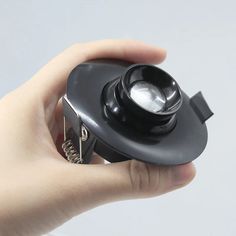 a hand holding a small black object in it's right hand, with the light on