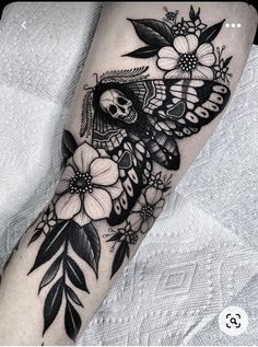 a black and white tattoo on the arm of a woman with flowers in her hair