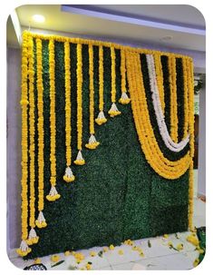 yellow and white garlands hanging from the side of a green wall with flowers on it