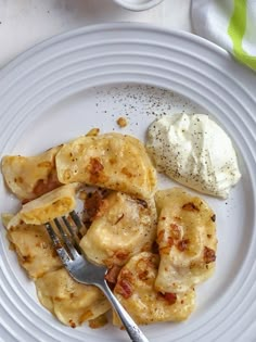 a white plate topped with ravioli next to a scoop of ice cream and a fork