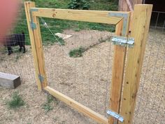 a black dog standing behind a fence in a yard next to a wooden post and wire