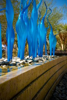 several blue glass sculptures sitting on top of a stone wall