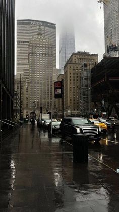 a city street with cars parked on the side of it and tall buildings in the background