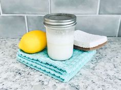 a mason jar sitting on top of two blue towels next to a lemon and a sponge