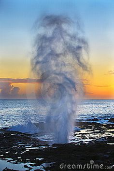 an ocean spray spewing water at sunset