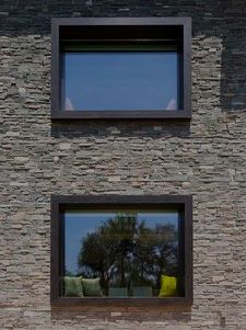 two windows on the side of a brick building with pillows and trees in the background