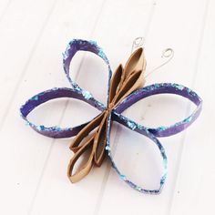 an ornament made out of paper and scissors on a white table with blue speckles