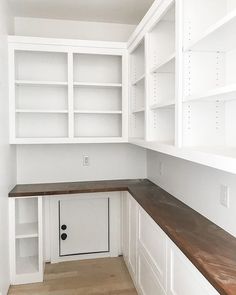 an empty kitchen with white cabinets and wood counter tops, including the door to the pantry