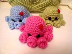 three crocheted stuffed animals sitting next to each other on a white surface with balls of yarn in the background