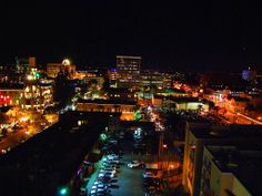 an aerial view of a city at night with cars parked on the street and buildings lit up