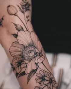 a woman's arm with black and white flowers on the left side of her arm