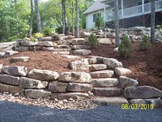 a large rock retaining wall in front of a house