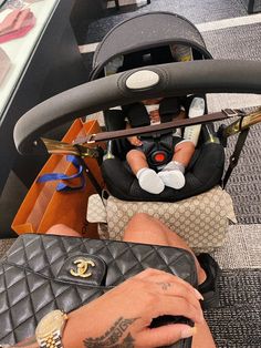 a woman sitting in a car seat with her hand on the baby's purse