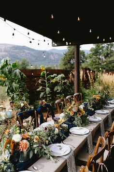 a long table is set up with plates and place settings for an outdoor dinner party