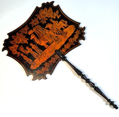 an ornate wooden fan with intricate designs on the top and sides, mounted against a white wall