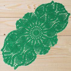 the green doily is laying on top of the wooden floor, ready to be crocheted