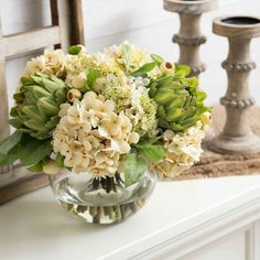 a vase filled with flowers sitting on top of a white table next to two candles