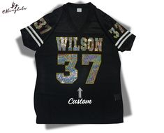 PLEASE READ BEFORE ORDERING: Personalize your Football Jersey. **All basic colors available **Shipping of this item takes 5 business days.  Includes Custom Team name and number on the front.   Player name and number on the back and sleeves **The iron on transfer option includes 1 design for the front. **Shirt is not included. 1️⃣✨Please let us know Team name and name and numbers  for the back After receiving your information and your order is placed, our specialized graphic design team will create a professional mockup and send it to you within 1-4 business days, with most cases being completed within 1 day. Please ensure that your Etsy messages notifications are turned on to avoid delays. 2️⃣ Shirt Description: Ladies regular fit **Please check size chart before ordering.  100% Polyester Customizable Fitted T-shirt For Sports Events, Rhinestone Jersey, Bling Football Jersey, Black Custom Print Jersey For Football Season, Customizable Jersey T-shirt For Sports, Sports Jersey Top With Number Print, Custom Bling, Personalized Jersey, Spirit Jersey