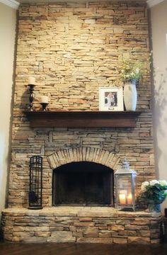 a stone fireplace with candles and pictures on the mantle