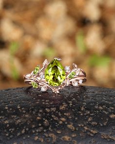 a yellow diamond ring sitting on top of a black piece of rock with leaves around it