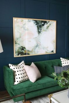 a living room with a green couch and paintings on the wall